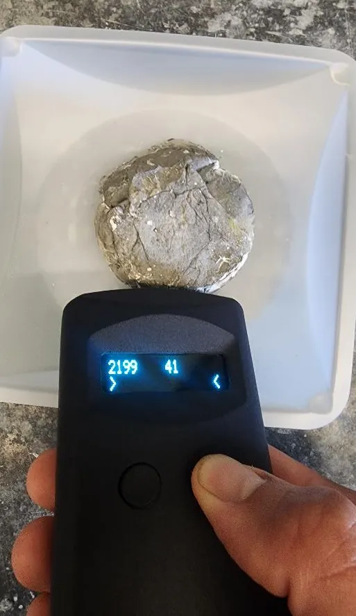 A hand holding a reader over a metal sample