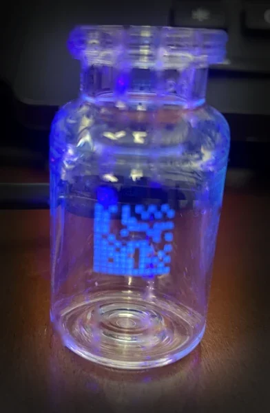 A vial with a printed data-matrix code glowing under UV