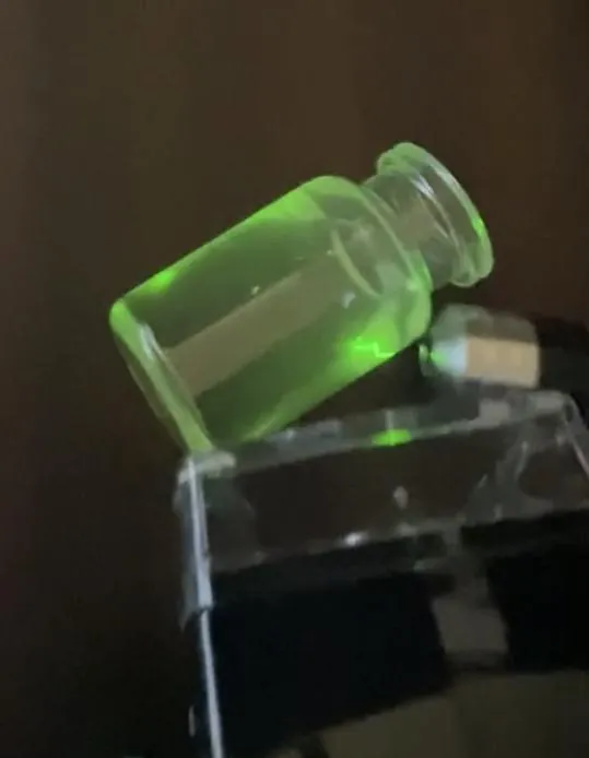 A vial glowing green under light